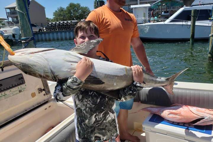 a man holding a fish on a boat