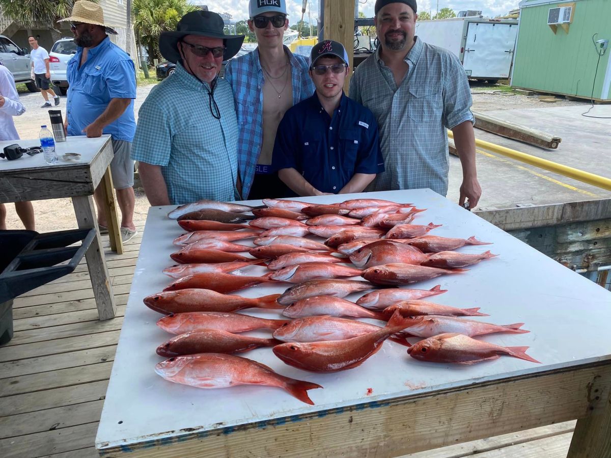northern red snapper a group of people standing on top of a cutting board with a cake